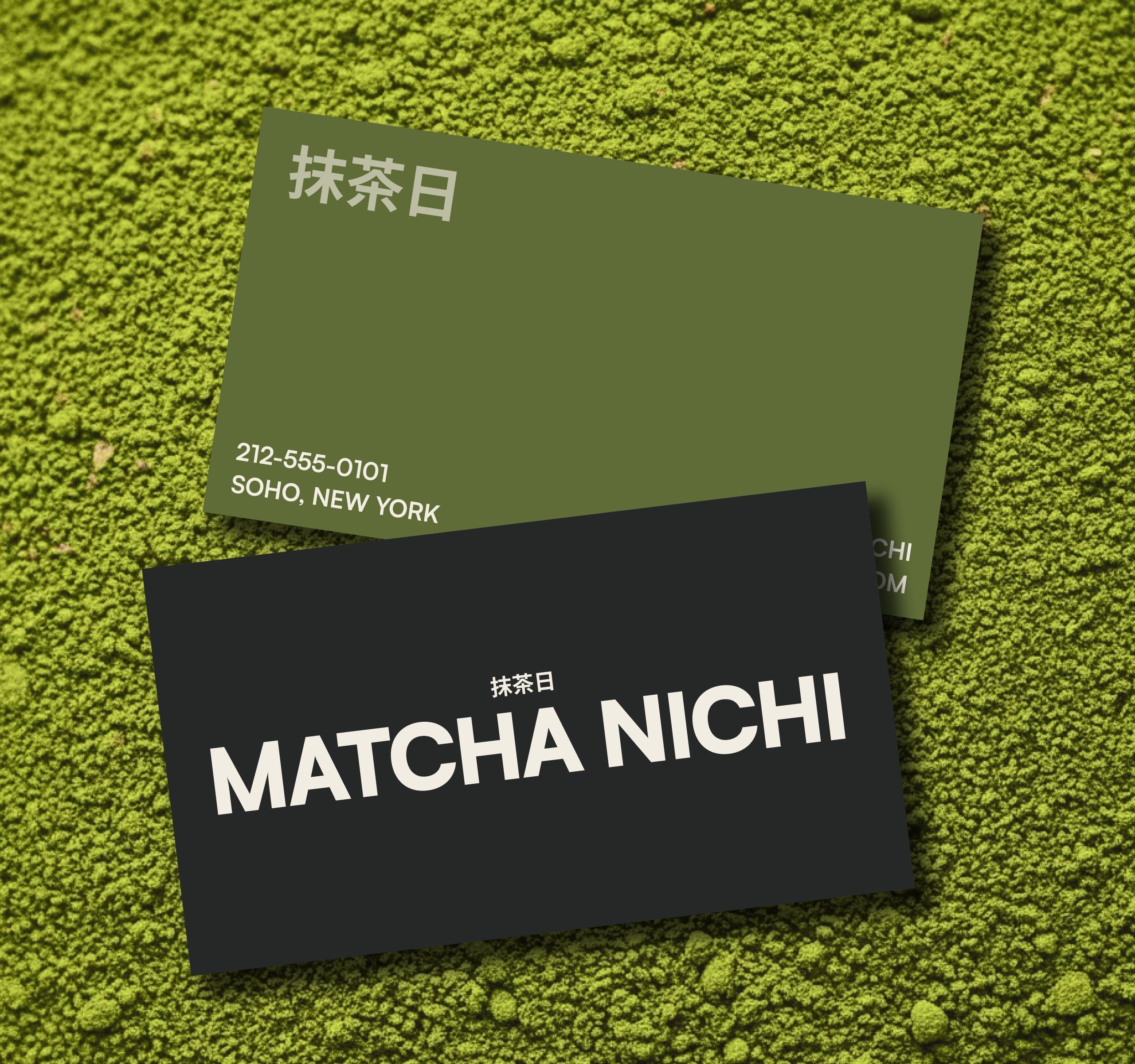 Two Matcha Nichi business cards on a bed of green matcha powder: an olive card with contact details and a charcoal card with the cream wordmark and Japanese logo.